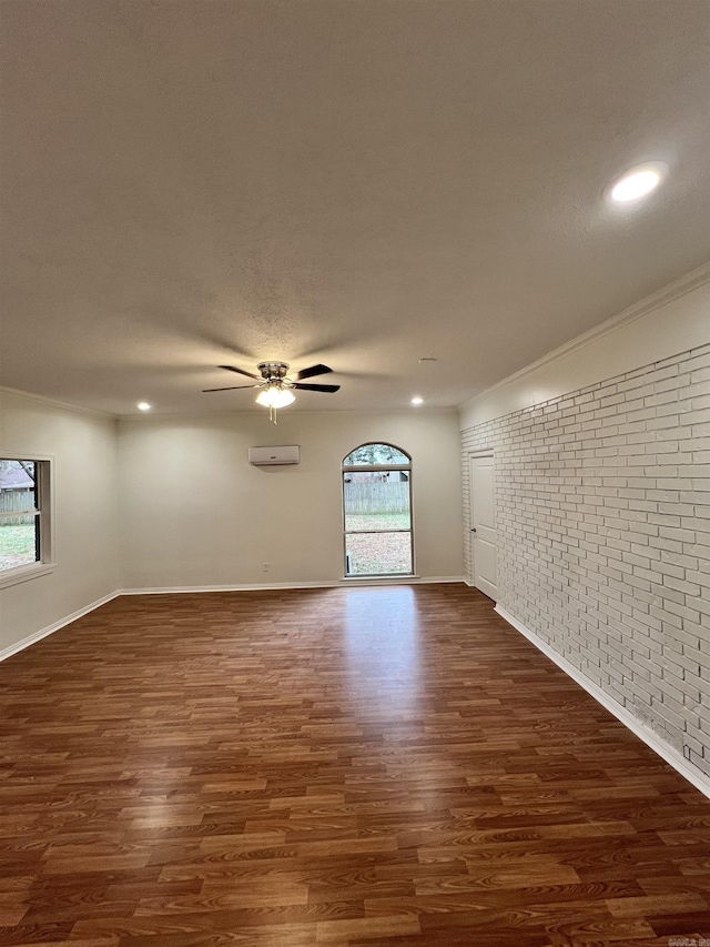 unfurnished room featuring ceiling fan, dark wood-type flooring, brick wall, a wall mounted AC, and ornamental molding