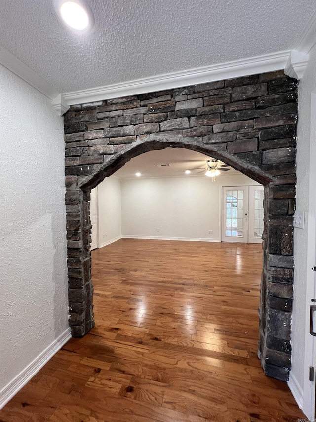 unfurnished living room with ceiling fan, hardwood / wood-style floors, crown molding, and a textured ceiling