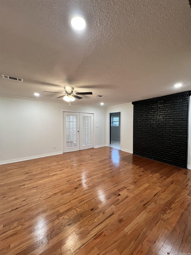 empty room featuring ceiling fan, french doors, wood-type flooring, and a textured ceiling