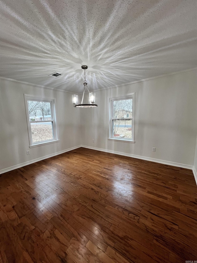 spare room with plenty of natural light, crown molding, dark wood-type flooring, and an inviting chandelier