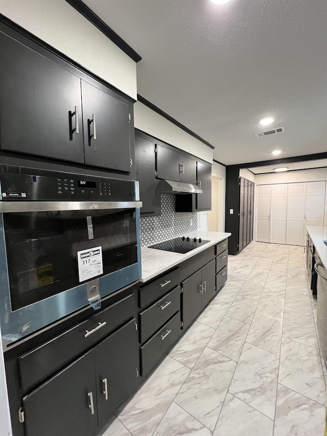 kitchen featuring black electric stovetop, oven, decorative backsplash, and extractor fan