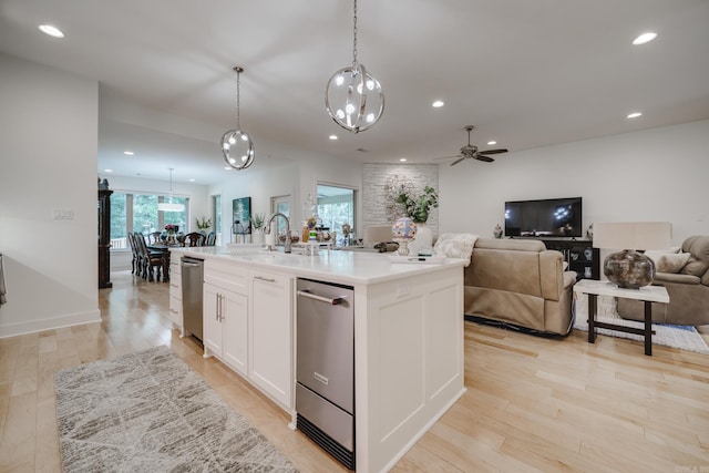 kitchen with ceiling fan, sink, decorative light fixtures, white cabinetry, and an island with sink