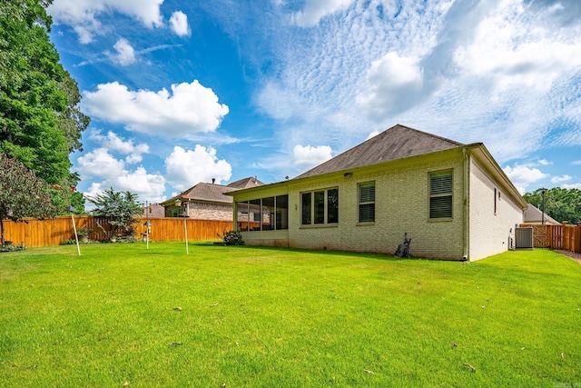 back of property with a yard and central AC