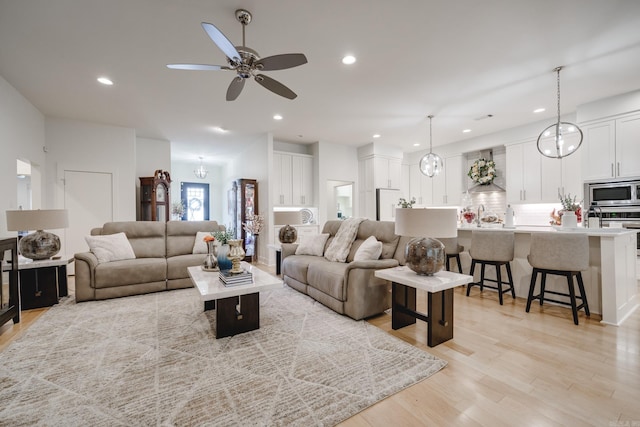 living room with ceiling fan, light wood-type flooring, and sink