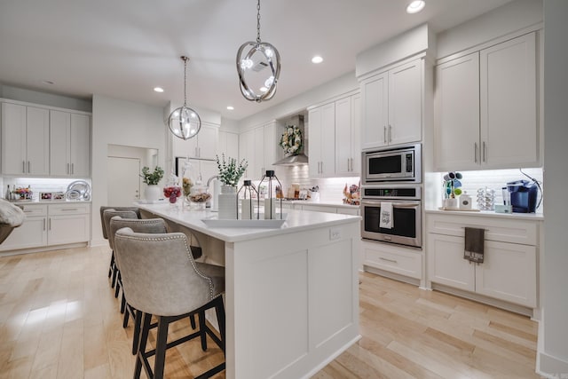 kitchen featuring backsplash, white cabinetry, hanging light fixtures, and appliances with stainless steel finishes