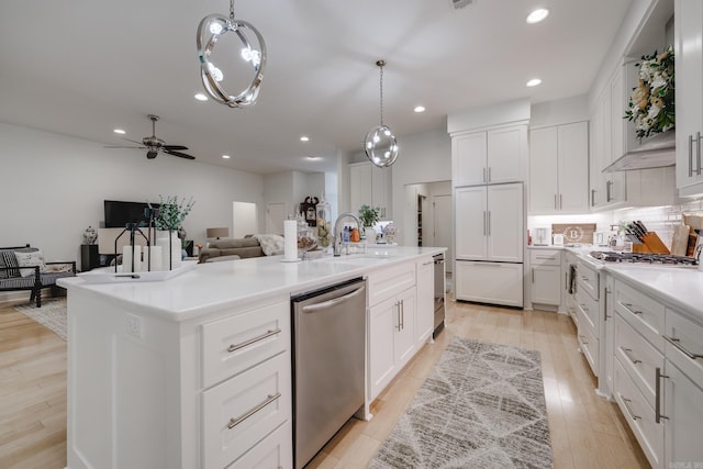 kitchen featuring white cabinetry, sink, stainless steel appliances, an island with sink, and decorative light fixtures