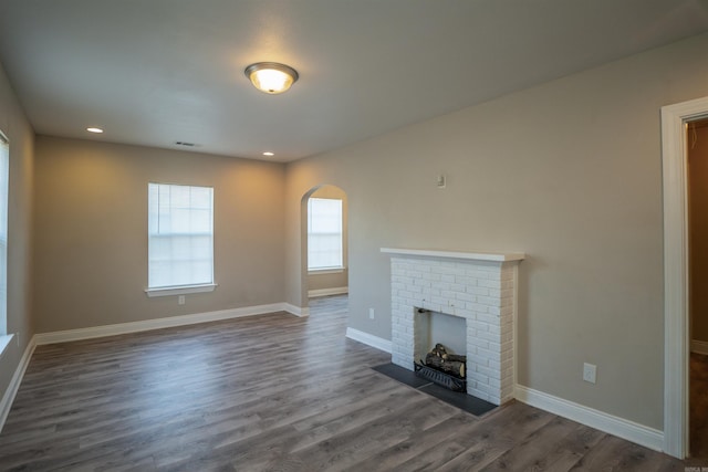 unfurnished living room with dark hardwood / wood-style flooring and a brick fireplace