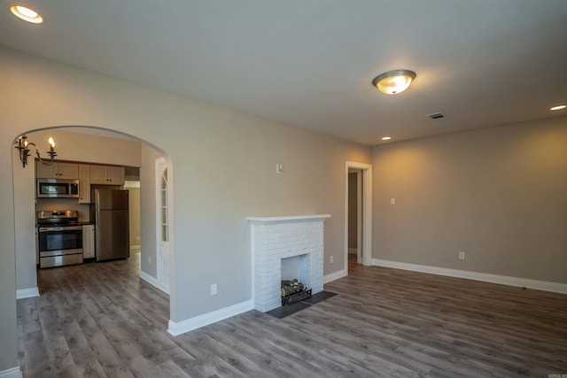 unfurnished living room with hardwood / wood-style floors and a brick fireplace