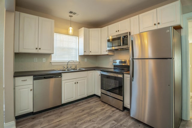 kitchen featuring decorative backsplash, appliances with stainless steel finishes, sink, hardwood / wood-style floors, and white cabinetry