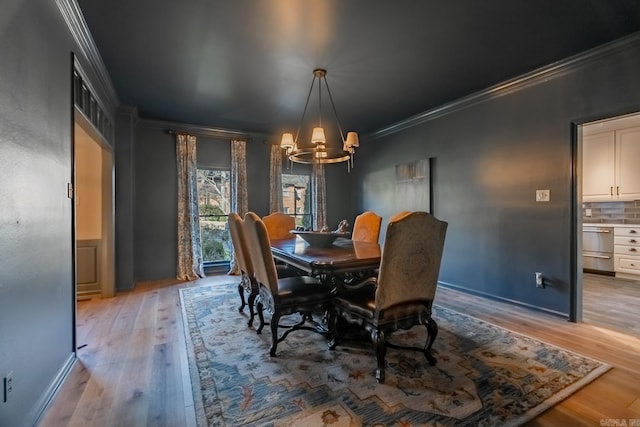 dining space with light hardwood / wood-style floors, an inviting chandelier, and ornamental molding