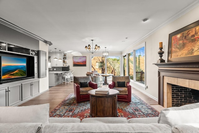 living room with wood-type flooring, ornamental molding, and a tiled fireplace