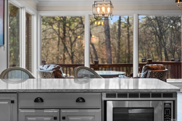 interior space featuring decorative light fixtures, white cabinetry, an inviting chandelier, and ornamental molding