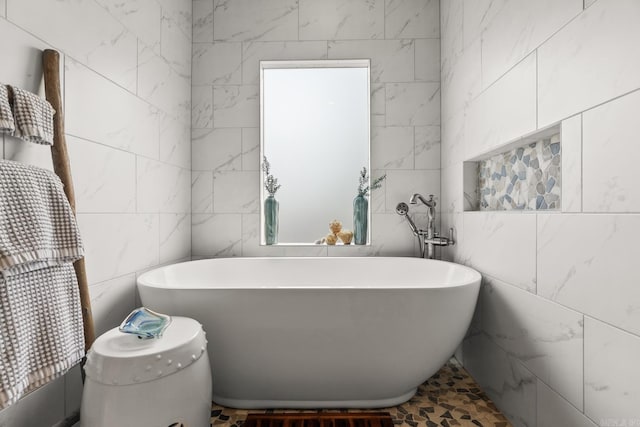 bathroom with a bathing tub and tile walls