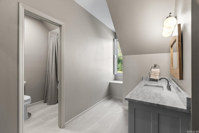 bathroom featuring toilet, vanity, and vaulted ceiling