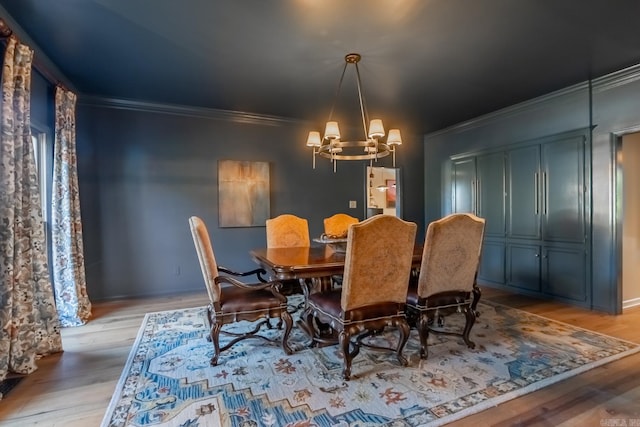 dining area with light wood-type flooring, ornamental molding, and a chandelier