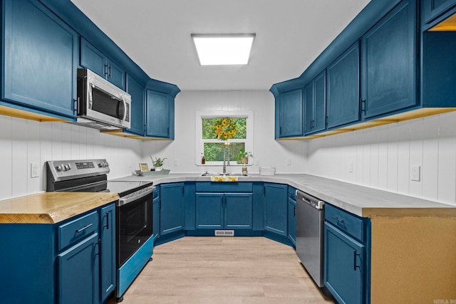 kitchen featuring blue cabinetry, sink, appliances with stainless steel finishes, and light hardwood / wood-style flooring