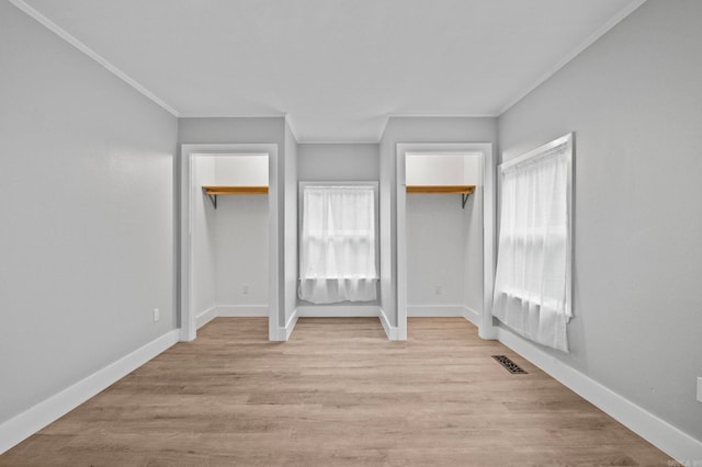 unfurnished bedroom featuring a walk in closet, light hardwood / wood-style flooring, and multiple windows