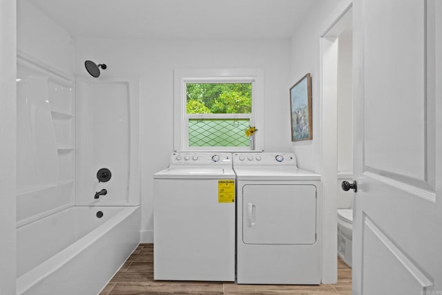 clothes washing area with washer and clothes dryer and hardwood / wood-style floors