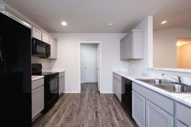 kitchen with gray cabinetry, black appliances, sink, vaulted ceiling, and dark hardwood / wood-style floors