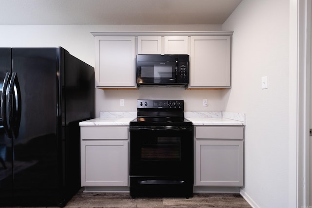 kitchen with dark hardwood / wood-style floors, gray cabinets, and black appliances