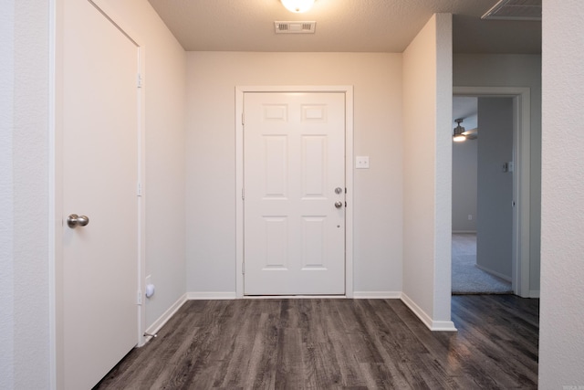 foyer entrance featuring a textured ceiling, ceiling fan, and dark wood-type flooring