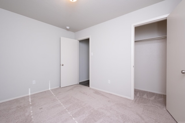 unfurnished bedroom featuring light carpet and a closet