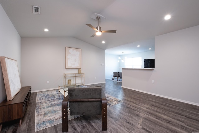 living room with ceiling fan with notable chandelier, lofted ceiling, and dark wood-type flooring