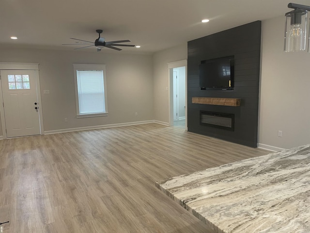 unfurnished living room with ceiling fan, light hardwood / wood-style floors, and a fireplace