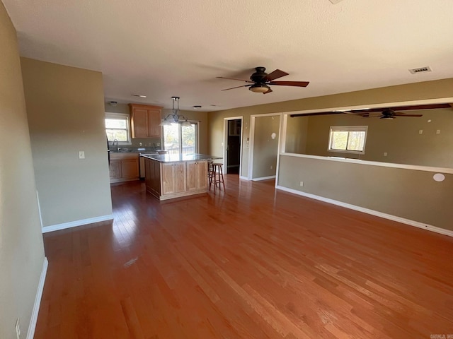 unfurnished living room featuring sink, dark wood-type flooring, and ceiling fan with notable chandelier