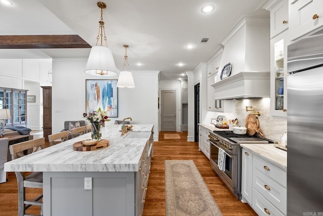 kitchen with white cabinetry, a breakfast bar, a kitchen island, custom range hood, and high end appliances