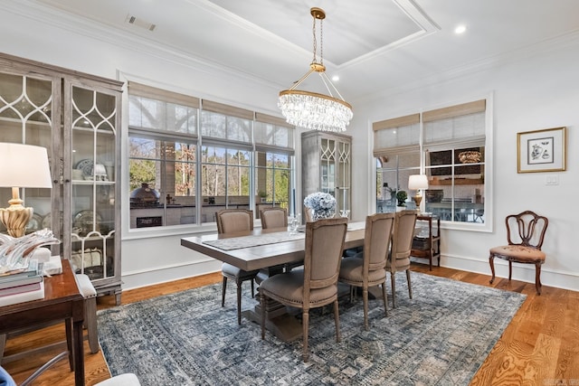 dining space with hardwood / wood-style flooring, crown molding, and a notable chandelier