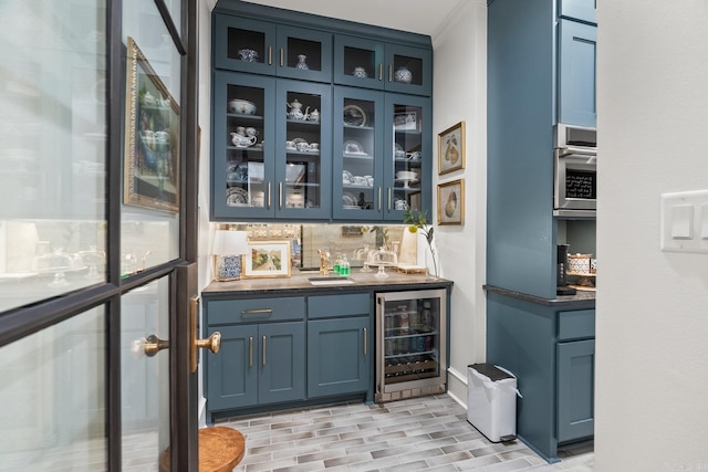 bar featuring blue cabinetry, decorative backsplash, oven, and beverage cooler