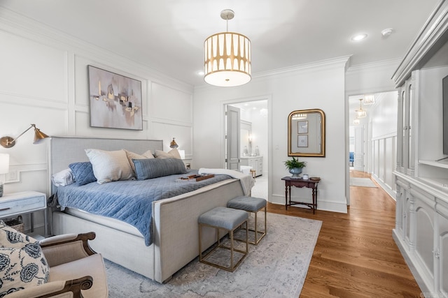 bedroom with dark hardwood / wood-style flooring, ornamental molding, and ensuite bath