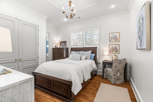 bedroom with an inviting chandelier, dark hardwood / wood-style flooring, ornamental molding, and a closet