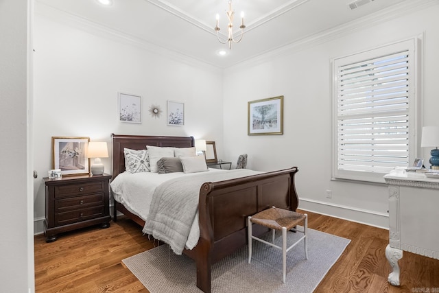 bedroom with hardwood / wood-style floors, a notable chandelier, and crown molding