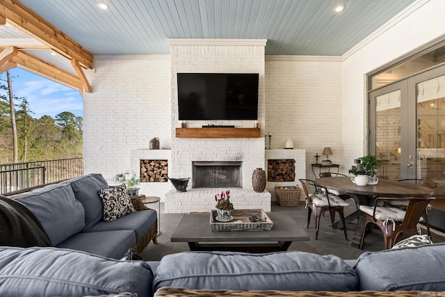 interior space with french doors, a brick fireplace, and beam ceiling