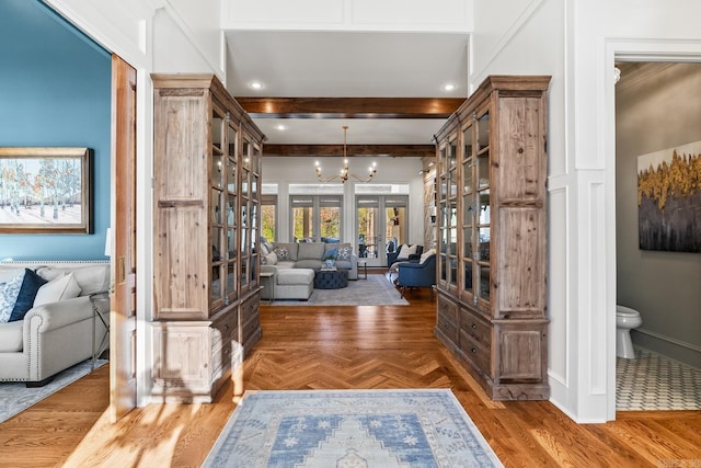 entryway with beam ceiling, dark parquet flooring, french doors, and a notable chandelier