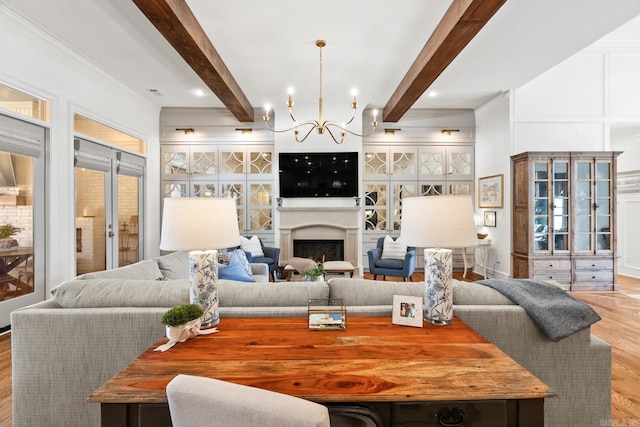 living room with beam ceiling, light hardwood / wood-style flooring, a chandelier, and french doors