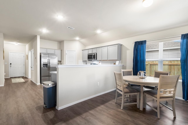 kitchen with gray cabinetry, dark hardwood / wood-style floors, appliances with stainless steel finishes, and vaulted ceiling