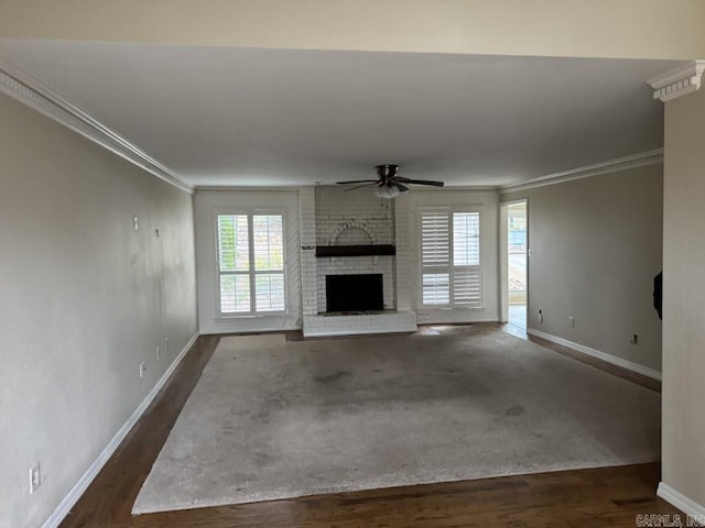 unfurnished living room featuring ceiling fan, dark hardwood / wood-style flooring, crown molding, and a fireplace