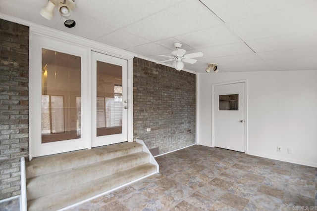 interior space with a paneled ceiling and ceiling fan