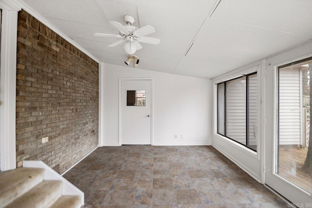 unfurnished sunroom with a drop ceiling and ceiling fan