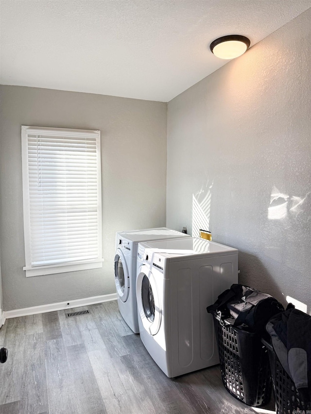 laundry room with washer and clothes dryer, wood-type flooring, and a wealth of natural light