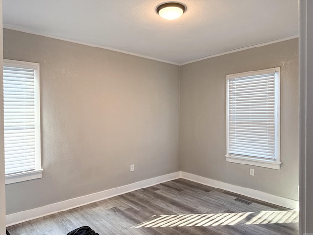 unfurnished room featuring hardwood / wood-style flooring, plenty of natural light, and crown molding