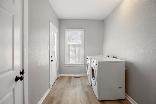 laundry area featuring washer and clothes dryer and light hardwood / wood-style floors