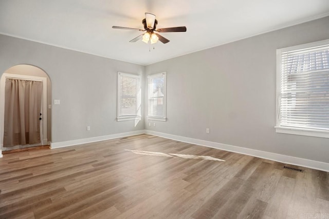 empty room with wood-type flooring, plenty of natural light, and ceiling fan