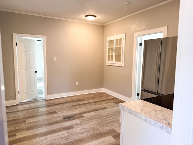 interior space with crown molding, a textured ceiling, and light wood-type flooring