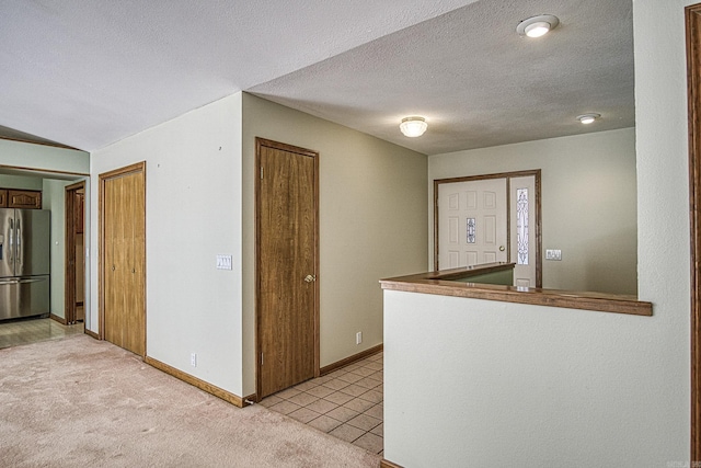 kitchen featuring stainless steel fridge, light carpet, and a textured ceiling