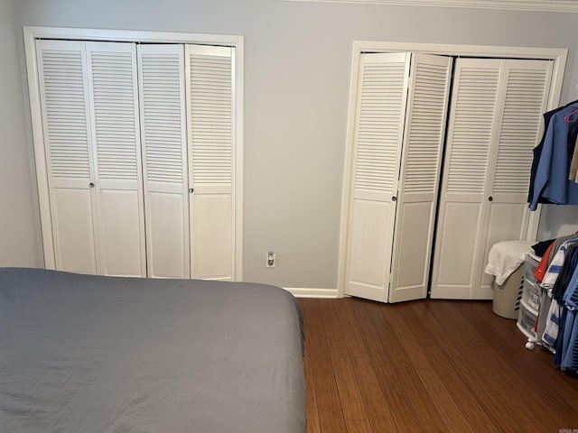 unfurnished bedroom featuring dark hardwood / wood-style flooring and multiple closets