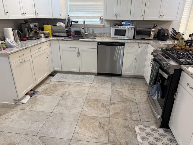 kitchen with light stone counters, sink, white cabinets, and appliances with stainless steel finishes